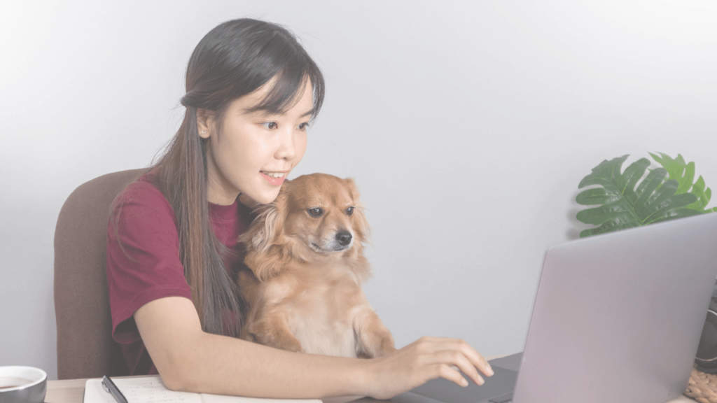 愛犬を抱きながらリモートワークをする女性