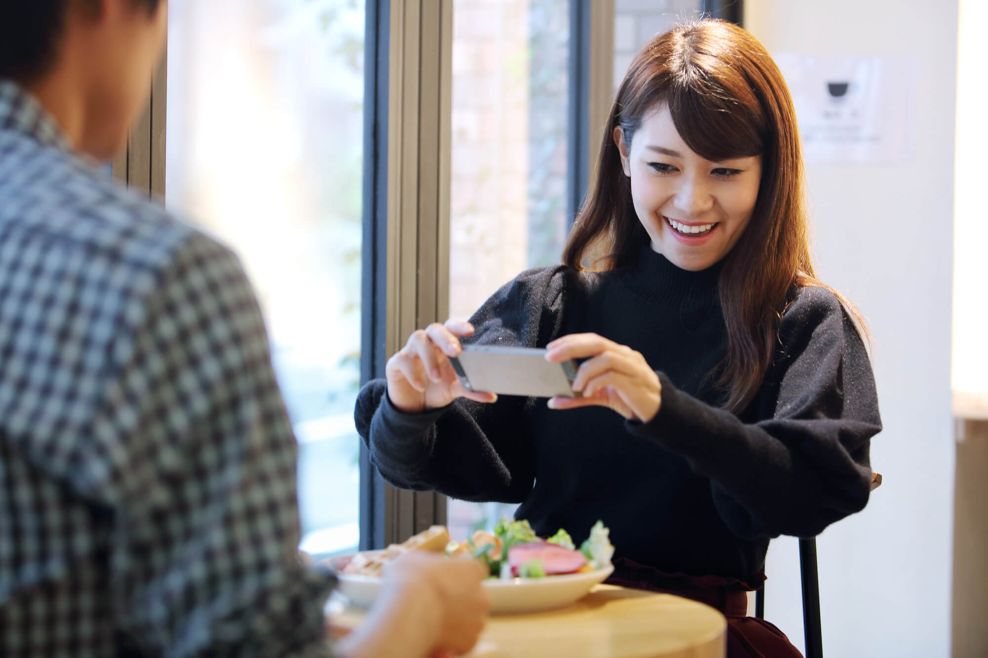 インスタにカフェの食事を投稿する女性